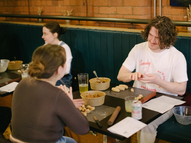 Couple sitting a restaurant table folding dumplings